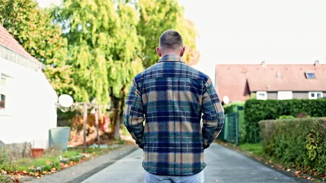 Back view of a man walking forward. A man walks through empty streets. Back view of a man in a coat. Autumn walk down the street.