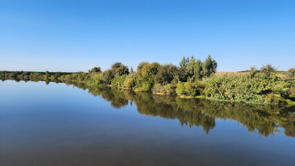 Fototapeta premium In Karataş Adana, Ceyhan River shines under the November sun, its calm waters capturing the colors of autumn