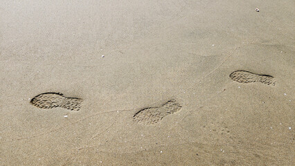 Footprints in the dune sand tell a quiet story of a solitary stroll along the shoreline