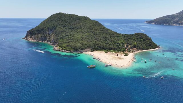 Aerial drone cinematic video of scenic caves and turquoise beach in paradise island of Marathonisi in bay of Laganas, visited by small boats a true tourist attraction, Zakithnos island, Ionian, Greece