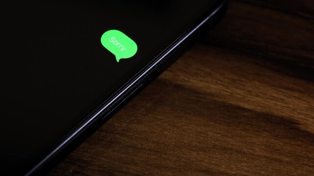 Close-up view of a smartphone screen showing an outgoing &ldquo;sorry&rdquo; text message in a green bubble, captured as it sends with a smooth popup animation.