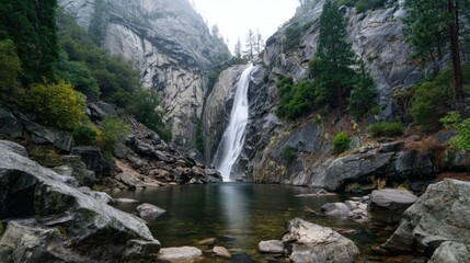 Majestic waterfall cascading down rocky cliffs in a misty forest during a calm morning