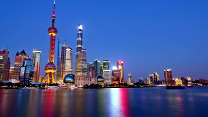 Night cityscape with illuminated skyscrapers reflecting in a river, with a passing boat