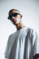 Obraz premium a young man in sunglasses wearing an oversized white t-shirt, against a white background.