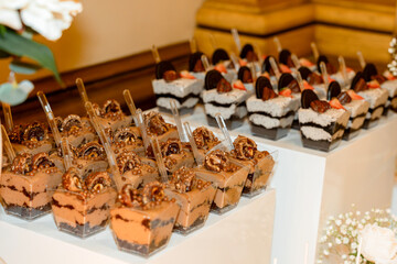 Assorted layered dessert cups with chocolate mousse, cookies, pretzels, and fresh fruit arranged on a decorative table. Elegant sweet buffet display for events and celebrations