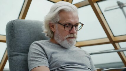 Senior man reading quietly in a cozy modern space. 4K Video