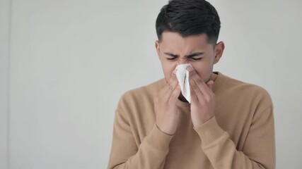 Man struggles with allergies while sneezing and using a tissue. 4K Video