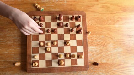Children hands moves to capture chess piece on wooden board