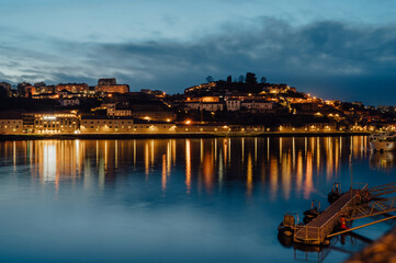Obraz premium Evening view of Douro River with lights reflecting on the water, Porto