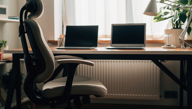Ergonomic home office setup with adjustable chair, clean desk, two laptops, minimalist decor, natural light, and indoor plant create productive and comfortable workspace