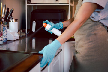 Female baker spraying cooking oil onto a tray.