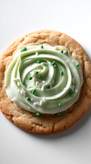 Fototapeta premium Homemade sugar cookie with green frosting swirl, white and green sprinkles, sweet dessert, closeup, delicious treat