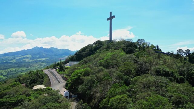 Slow rising aerial revealing the towering Mt. Samat National Shrine surrounded by lush forested hills, with sweeping views of valleys and mountains in Pilar, Bataan, Philippines.
