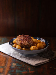 Fried meatballs with potatoes on a rustic background. Selective and soft focus.