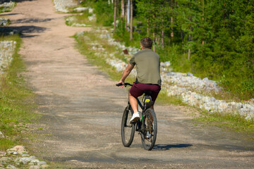 Obraz premium Man with Bicycle on Road Near Green Park in Summer