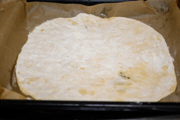 Rolled Pizza Dough on Baking Paper in Tray Ready for Homemade Pizza