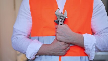 Professional plumber in orange safety vest holding adjustable wrench. Ready for maintenance, repair, or construction work. Confident and skilled, symbolizing dedication to trade.
