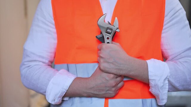 Professional plumber in orange safety vest holding adjustable wrench. Ready for maintenance, repair, or construction work. Confident and skilled, symbolizing dedication to trade.