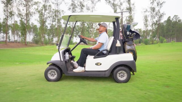 Asian couple golfers ride together in golf cart on scenic golf course. 