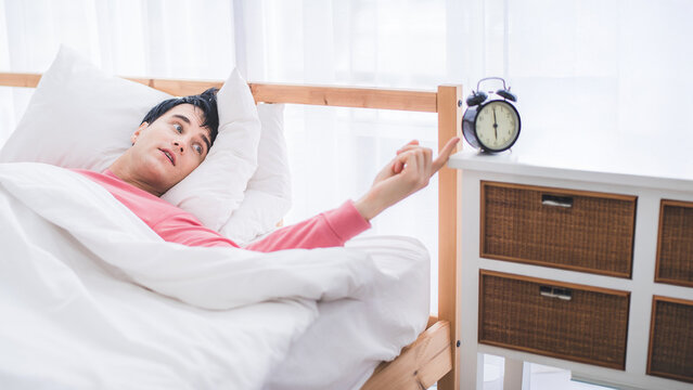 sleepy man on the bed with alarm clock in the morning