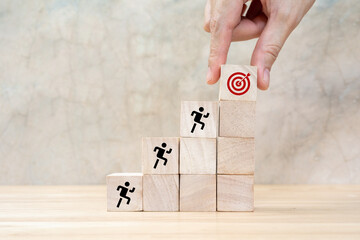Common goal success concept. Teamwork rises up stairs to goal and achieve successful business. Initiation for planning to reach target. Darts target aim icon on wooden cubes with grey background.