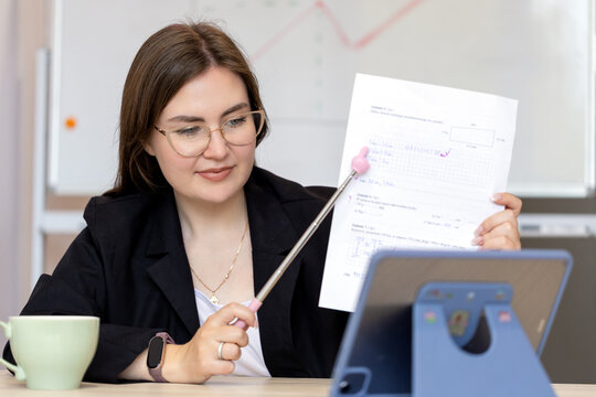 A math teacher conducts an online lesson using a whiteboard and tablet. Online learning