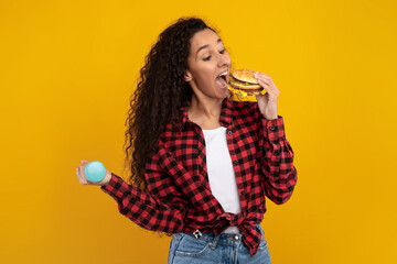 A funny scene where a woman holds a large burger in one hand and a dumbbell in the other. She...