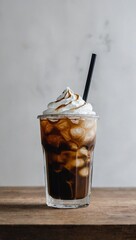 A glass filled with coffee, with ice, whipped cream and a straw.