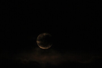 Full moon in dark night sky , lunar moon with clouds, closeup of photo.