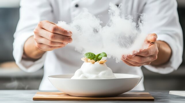Chef adds smoke to an artistic dessert creation, showcasing molecular gastronomy techniques with white clouds of vapor and a mint garnish.