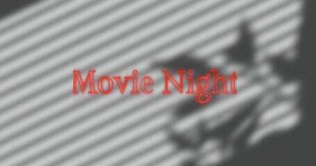 Projecting red text Movie Night at home, blinds casting diagonal shadows, blurred silhouette right