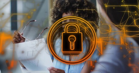 Reviewing documents, woman in blue top holding glasses in office, padlock overlay and circuit lines