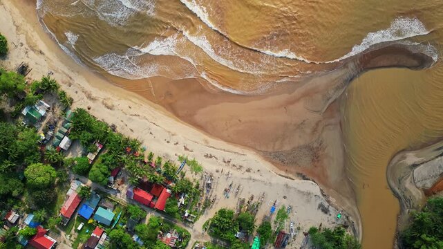 Rising rotating aerial capturing sandy shoreline of Quinawan Beach and foamy waters with waves rolling in, gradually revealing the coastline town and lush hills in Mariveles, Bataan.