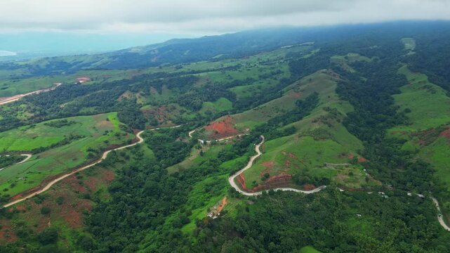 Bird&rsquo;s‑eye aerial of Bataanes in Bagac, Bataan, showing rolling green hills, winding roads, and coastal scenery with turquoise waters stretching toward the horizon.