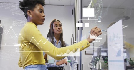Writing woman wearing yellow top sketching data on glass partition, holding marker, copy space
