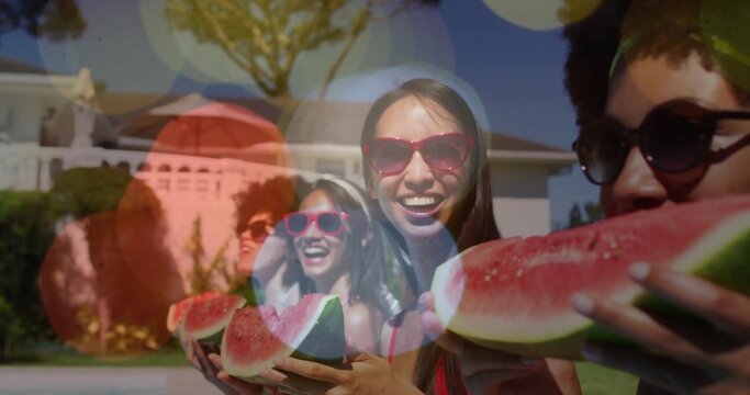 Smiling central woman holding watermelon slice at suburban yard, wearing red shades and tank tops