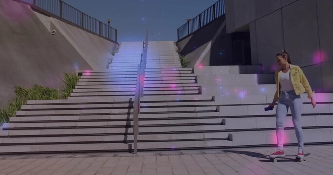 Standing woman in yellow jacket, jeans holding phone balancing on skateboard at stairs, copy space