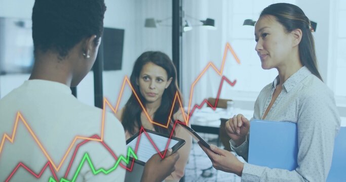 Reviewing tablets, three women in workwear viewing red orange green overlay blue-folder in office