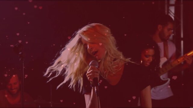 Lead singer singing into mic and flipping hair, initiating floating hearts during music set