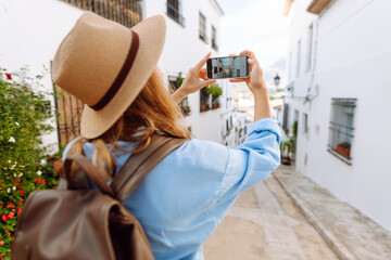 A beautiful woman in a hat stands in a busy square, holding a phone. A young tourist in sunglasses...