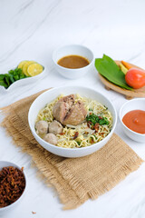 Delicious bakso or Indonesian traditional meatballs on bowl. Soup containing noodles, vegetables, and fried tofu
