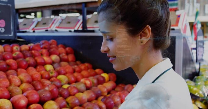 Female produce clerk spotting misaligned apples and reordering fruit while checking quality