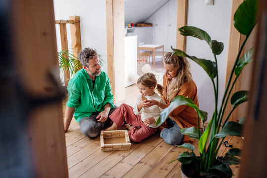 Parents with daughter playing block game in attic doorway