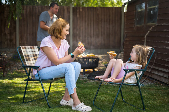 Family enjoying barbecue and burgers outdoors in garden in summer