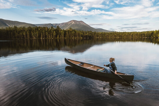 Solo female canoe paddler on Daicy Pond, Maine. Katahdin in distance