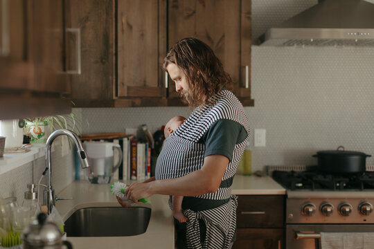 Stay at home dad babywearing and washing dishes