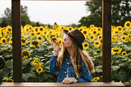 Teenage girl in cowboy hat kisses a flower in flowers fields
