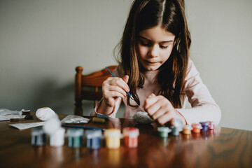 Young Girl Deep Painting a Rock at Home in Kitchen