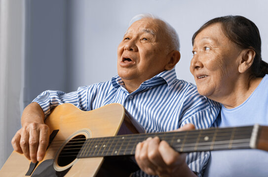 Senior man playing acoustic guitar with his wife