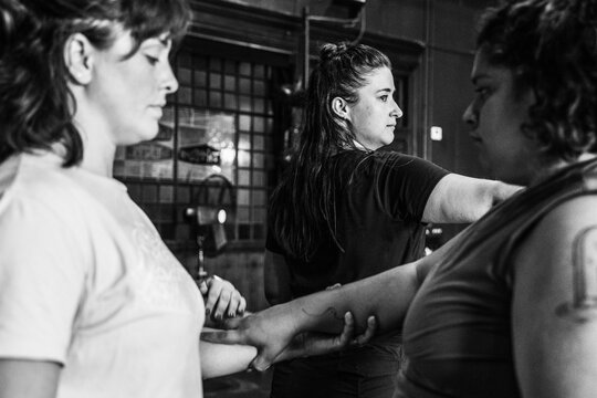 Three people hold a connected pose during a rehearsal